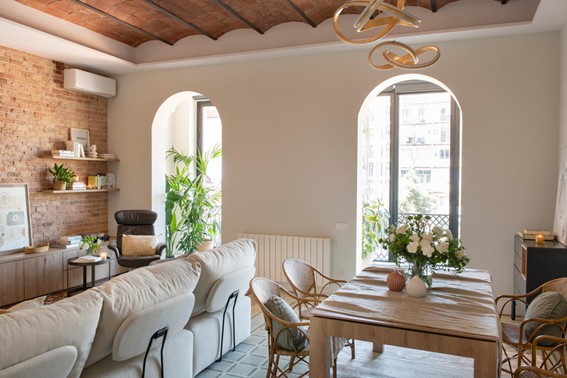 Salón-comedor luminoso en vivienda reformada del Eixample, con techos altos, molduras originales restauradas y mobiliario en tonos neutros. Detalle de bóveda catalana vista y pared de ladrillo caravista restaurada en vivienda reformada en Barcelona.